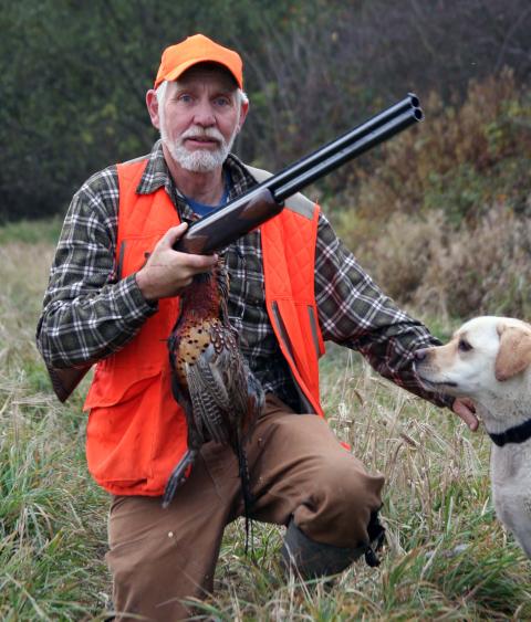 An older gentleman hunting with his dog