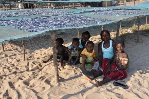 A family rests in the shade of nets used to dry fish